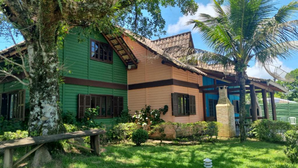 una casa verde con una palma di fronte di Chalé Carvalho - Azul a Itapoa