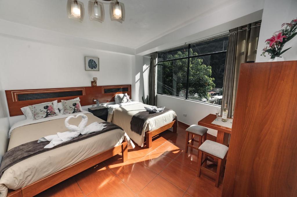 - une chambre avec 2 lits, un bureau et une fenêtre dans l'établissement Escobedo’s Inn Machupicchu, à Machu Picchu