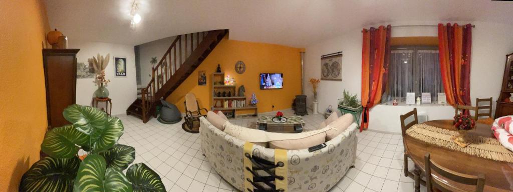 uma sala de estar com um sofá e um quarto com uma escada em La Cigale Ardéchoise em Labégude