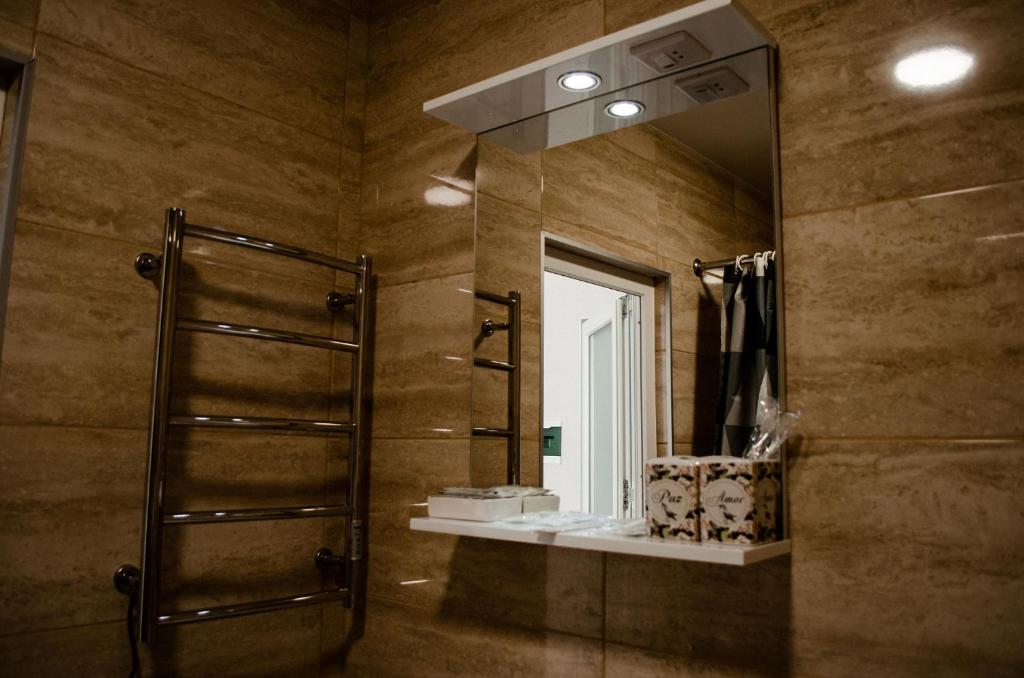 uma casa de banho com um chuveiro e um espelho grande em Гостьовий Будинок Апартаменти в тихому центральному районі Полтави Смарт-квартири em Poltava