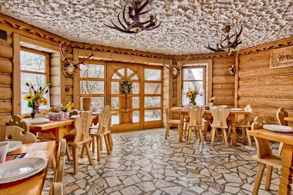 a restaurant with wooden walls and tables and chairs at Dom Wypoczynkowy GALICA in Poronin