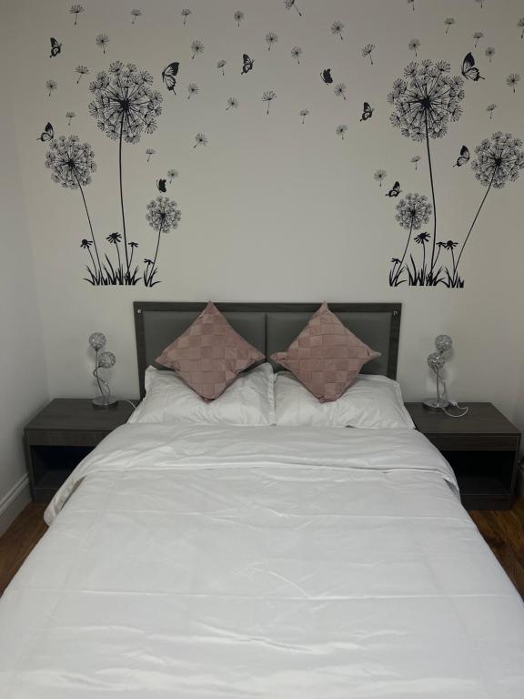 ein Schlafzimmer mit einem weißen Bett mit Löwenzahn an der Wand in der Unterkunft Cromer House in Horsham St Faith