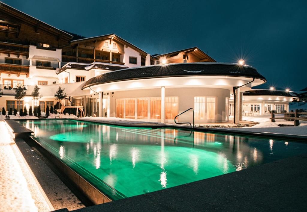 a swimming pool in front of a house at night at Naturhotel MOLIN in San Giovanni in Val Aurina