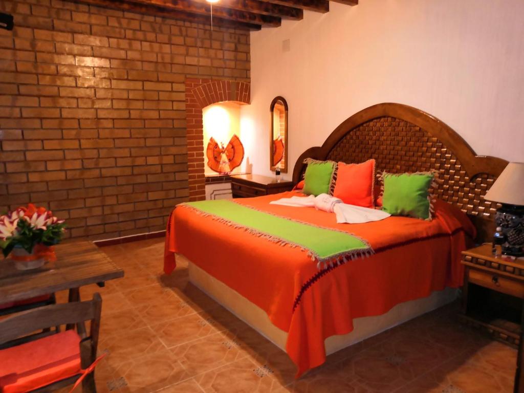 a bedroom with a bed with orange and green pillows at Hotel El Aguila in Villa del Carbón