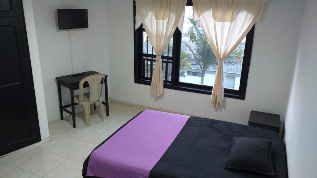 1 dormitorio con 1 cama de color púrpura y 2 ventanas en Casa la camelia en Manizales