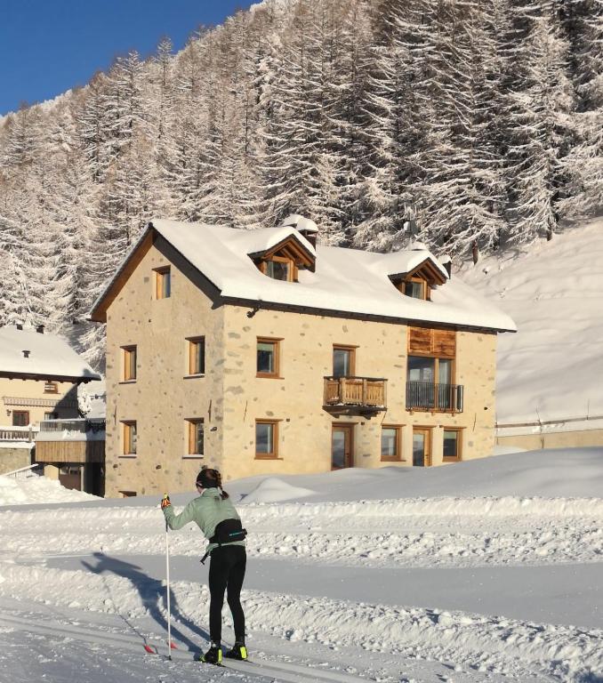 a person on skis in the snow in front of a house at Chalet Aria Pura in Livigno