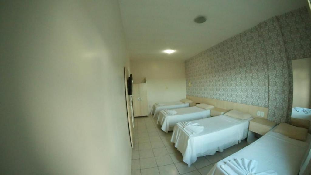 een kamer met drie bedden in een kamer bij Hotel Treviso in Linhares