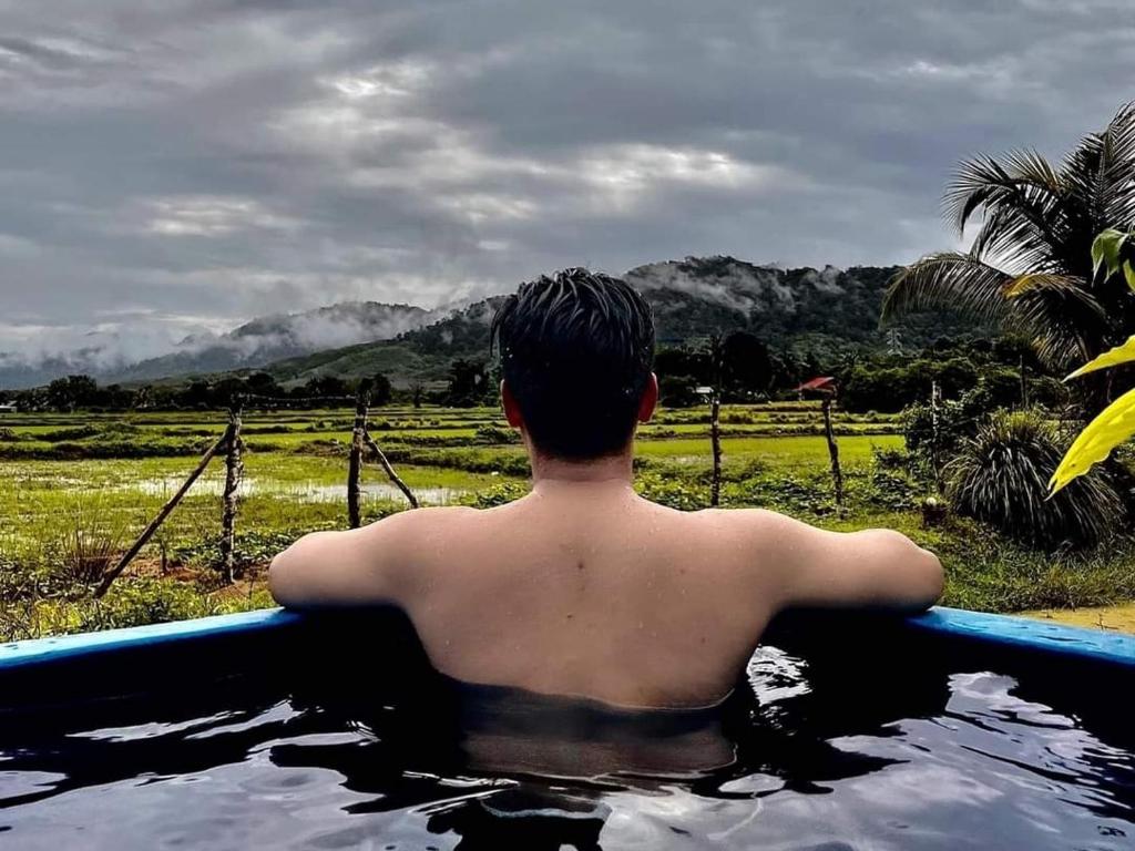 un jeune homme assis dans une baignoire dans une piscine d'eau dans l'établissement Villa Mak Intan, Che'Pa Village Langkawi, à Kuah