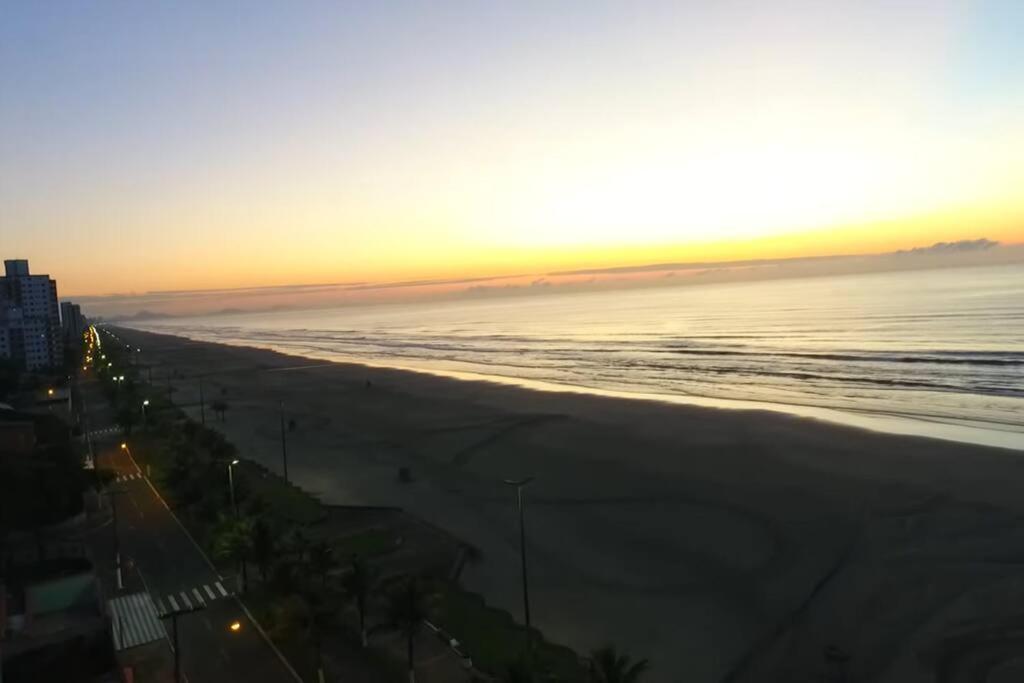 a view of the beach at sunset at Frente ao mar, conforto e paz apto 12 in Praia Grande