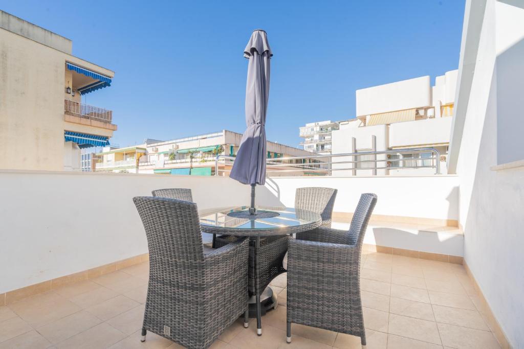 a table with chairs and an umbrella on a balcony at Apartamentos Castillo in Fuengirola