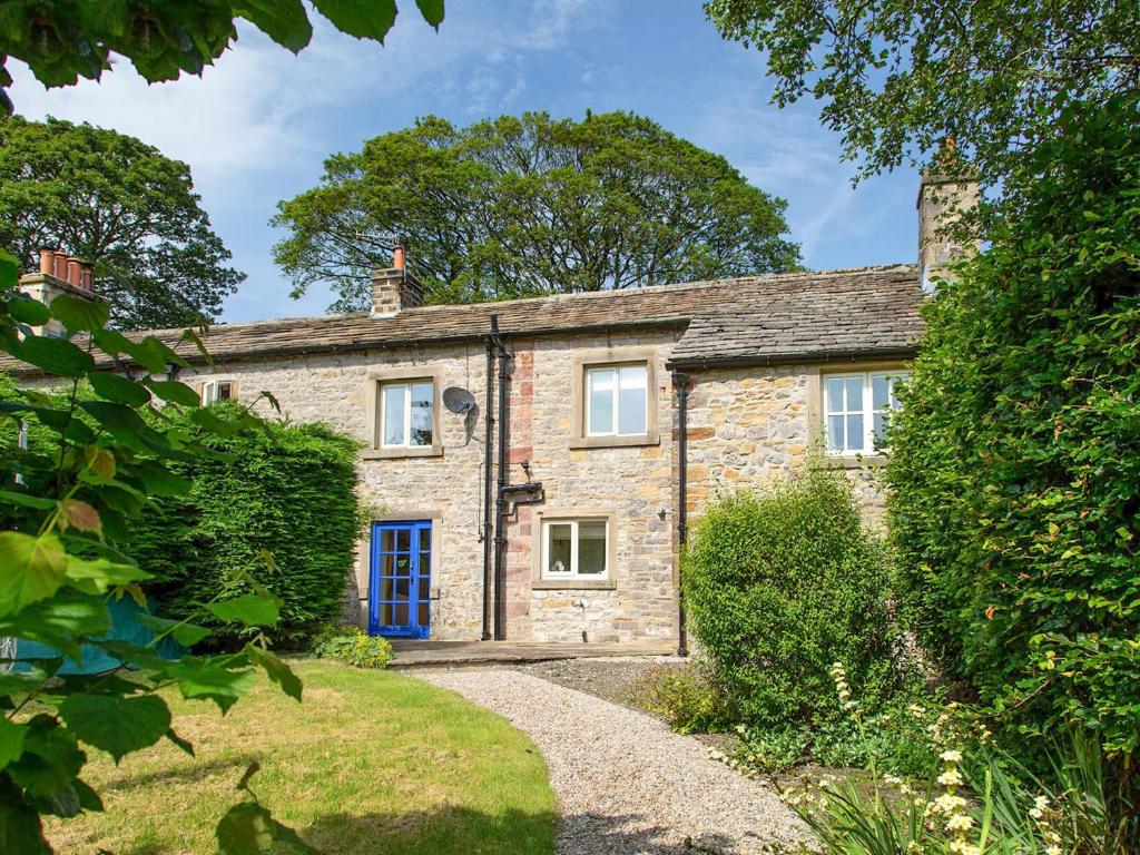 an old stone house with a blue door and a driveway at Gargrave Cottage - Uk42248 in Broughton