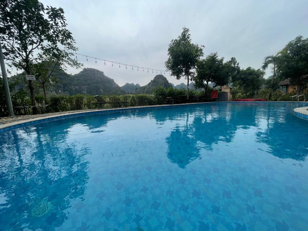 a large blue swimming pool with mountains in the background at Trang An Legend in Ninh Binh