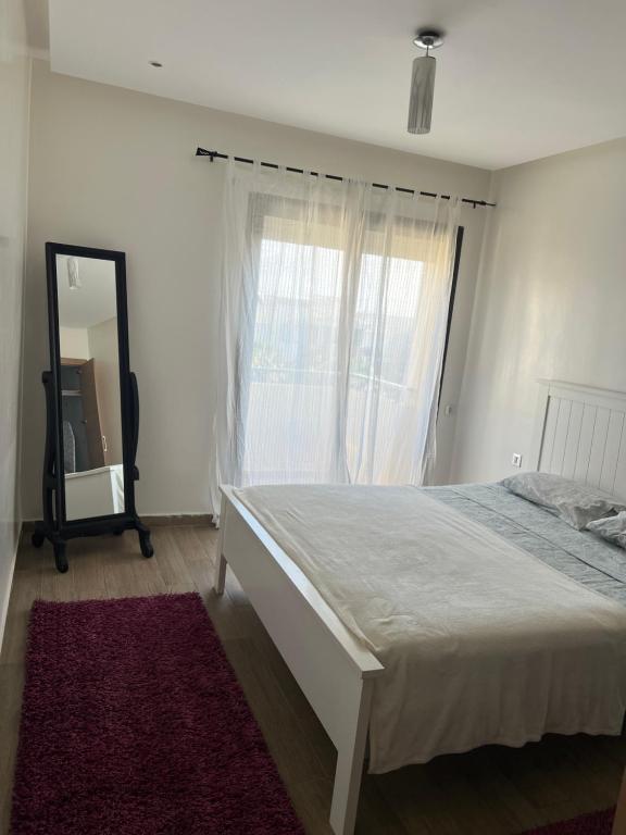um quarto com uma cama, um espelho e uma janela em Luxury Apartement Near the Beach em Sidi Bouqnadel