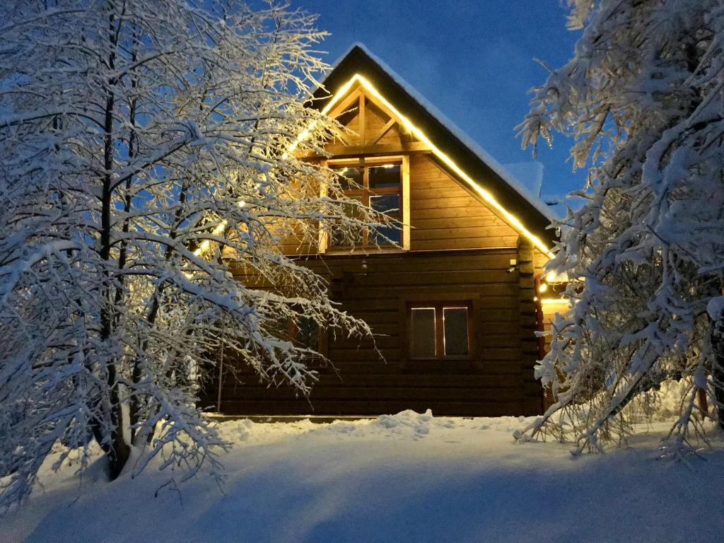 Una cabaña de troncos en la nieve con luces encendidas. en ZRUB BINDT, en Hnilčík