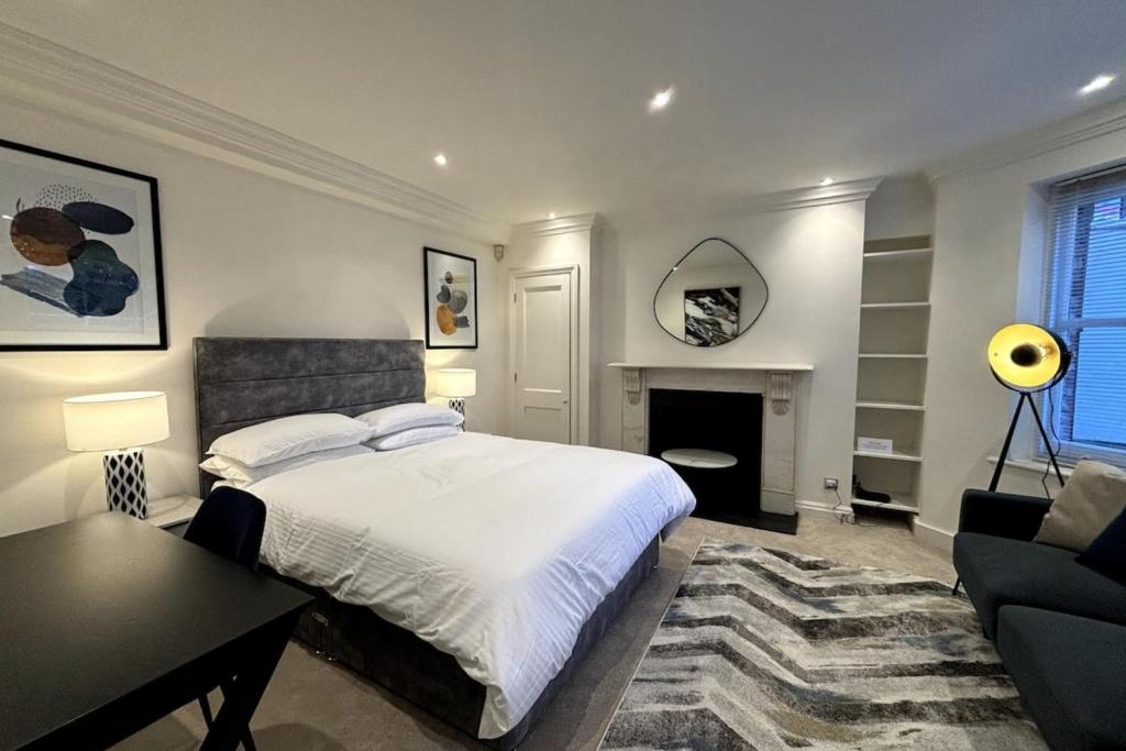 a bedroom with a bed and a table and a fireplace at Chic Studio Flat 8 Mins to Harrods Knightsbridge in London