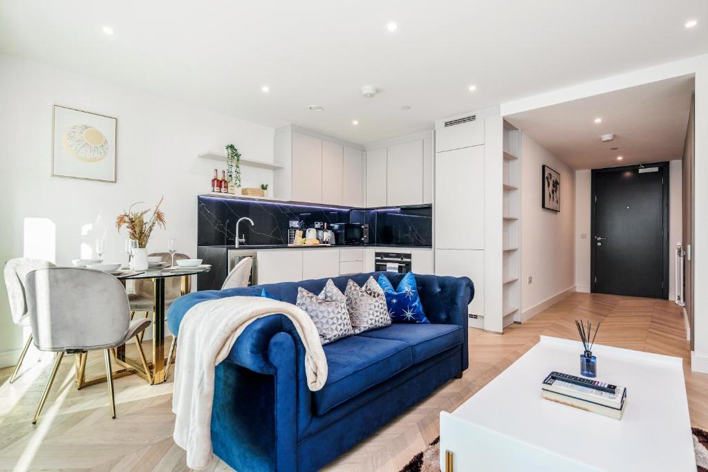ein Wohnzimmer mit einem blauen Sofa und einer Küche in der Unterkunft New Riverside Apt sleeps 5 Easy to tour London in London
