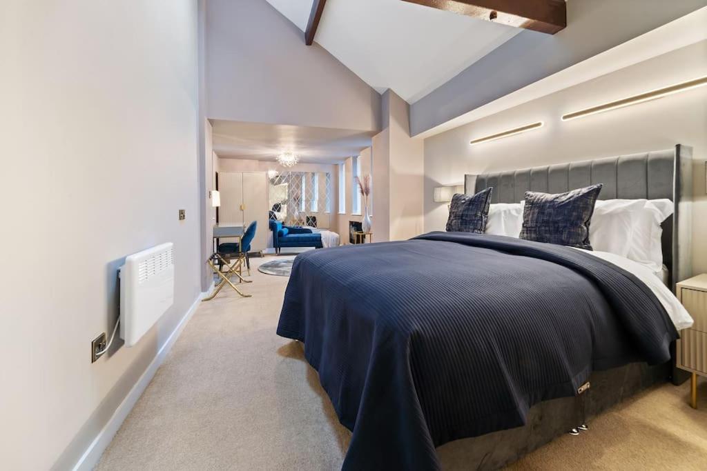 a bedroom with a large bed with a blue blanket at NEW Large luxurious 2 bed city penthouse + parking in Leicester