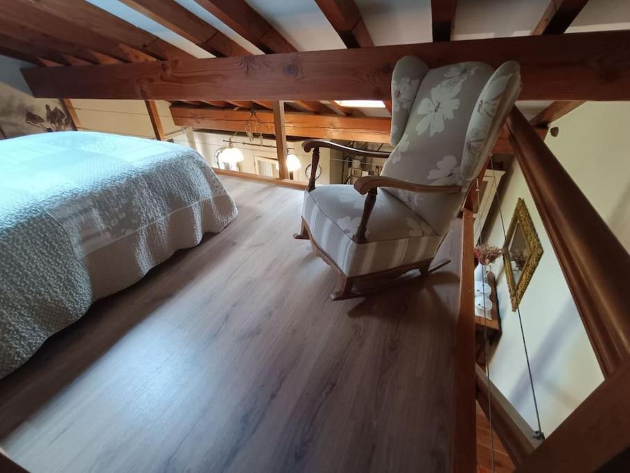 a bedroom with a bed and a chair on a wooden floor at Casa Coba 
