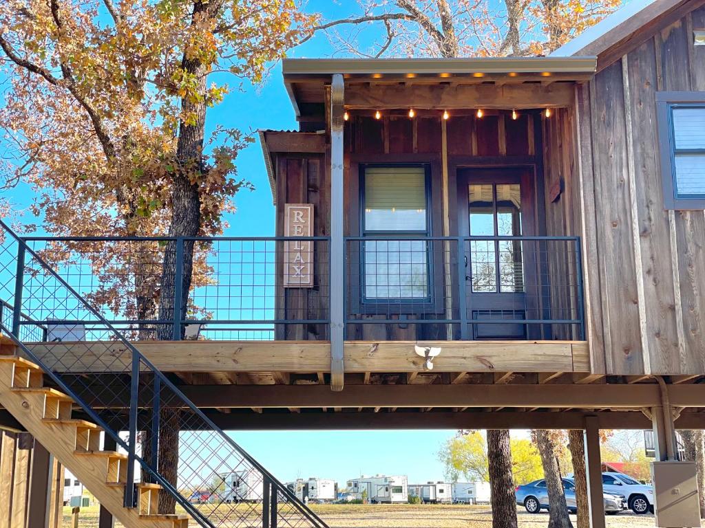 uma casa na árvore com um deque e escadas em The Wren Treehouse 15 MIN to Magnolia Baylor 