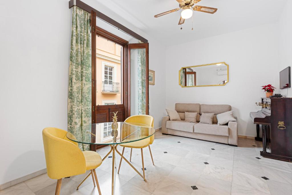 a living room with a glass table and yellow chairs at Trinidad Grund Centro in Málaga
