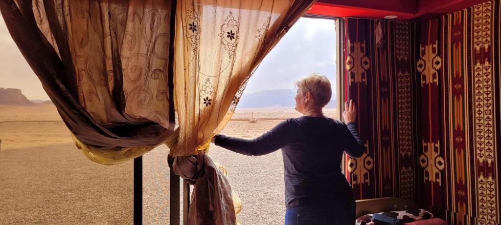 uma mulher olhando para fora de uma janela no deserto em Dream Bedouin life camp em Wadi Rum