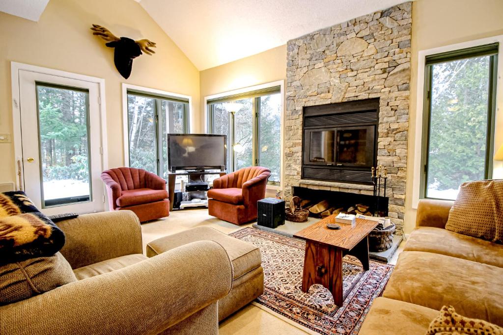 a living room with couches and a stone fireplace at Forest Hideaway in Waterville Valley