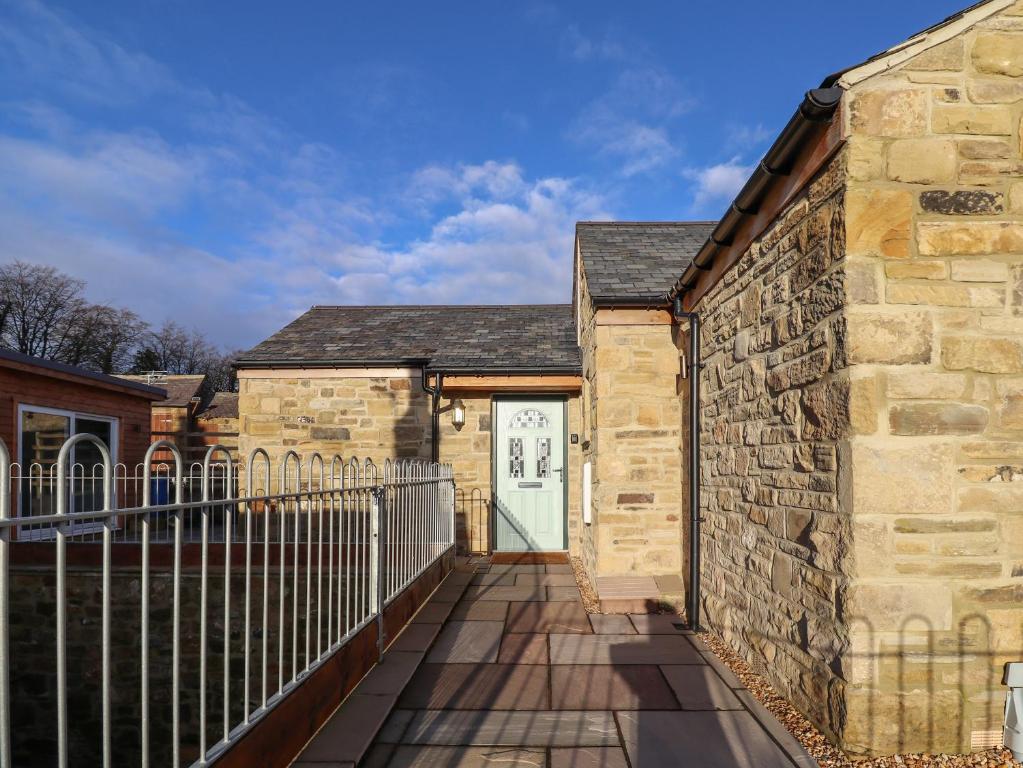 a stone building with a gate and a white door at Summerseats Cottage in Alnwick