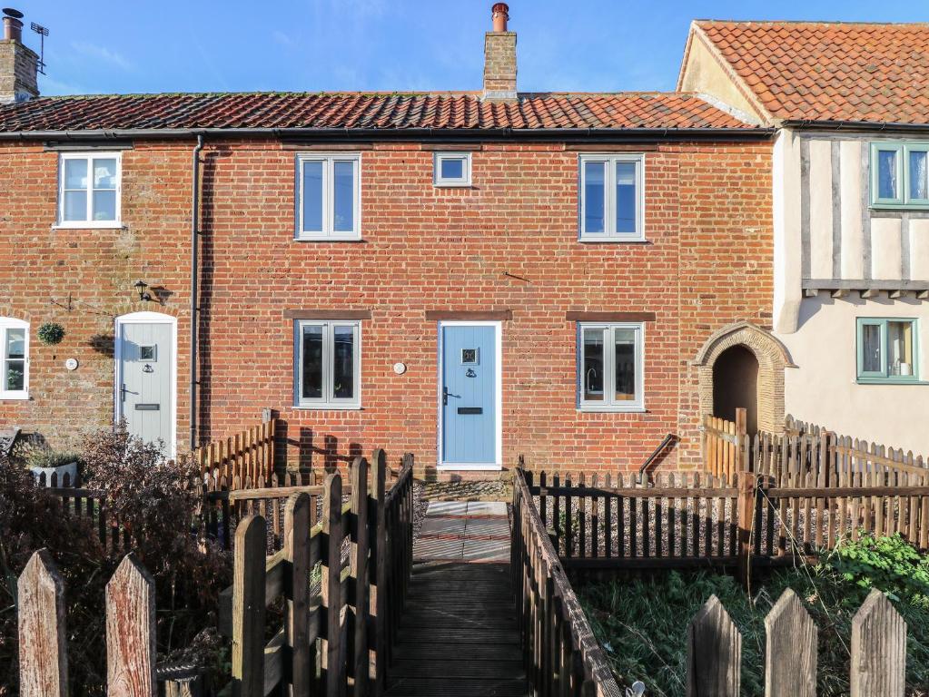 a brick house with a wooden fence in front of it at Spring Cottage in Norwich