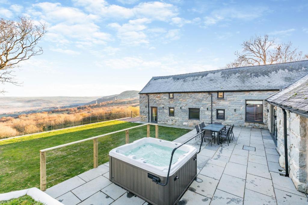 un patio al aire libre con bañera de hidromasaje y un edificio en Ysgubor Maen Y Bardd en Conwy