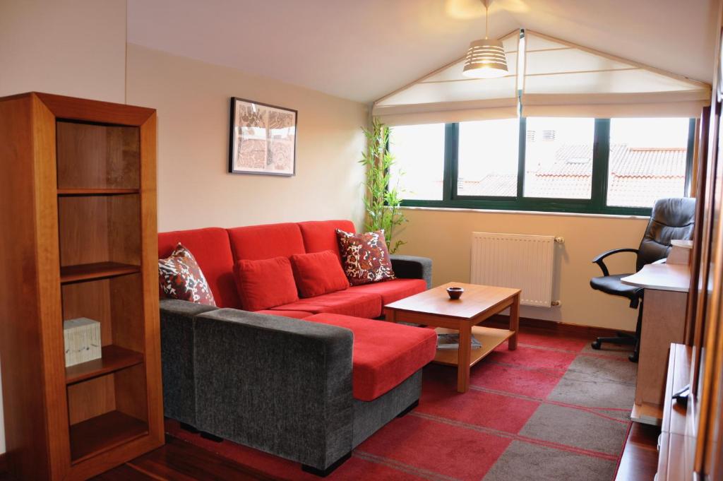 a living room with a red couch and a table at Alojamiento Santa Maria III in Milladoiro