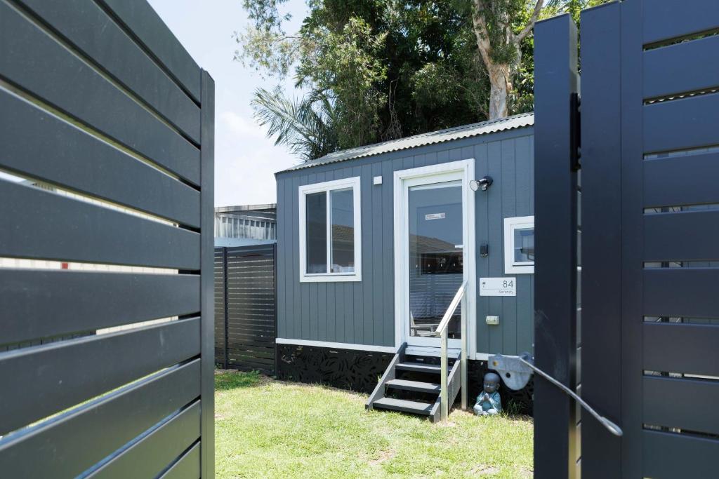 a blue tiny house next to a fence at Sweet beautiful TINY HOME with pool and 2 minute drive to the beach in Wollongong
