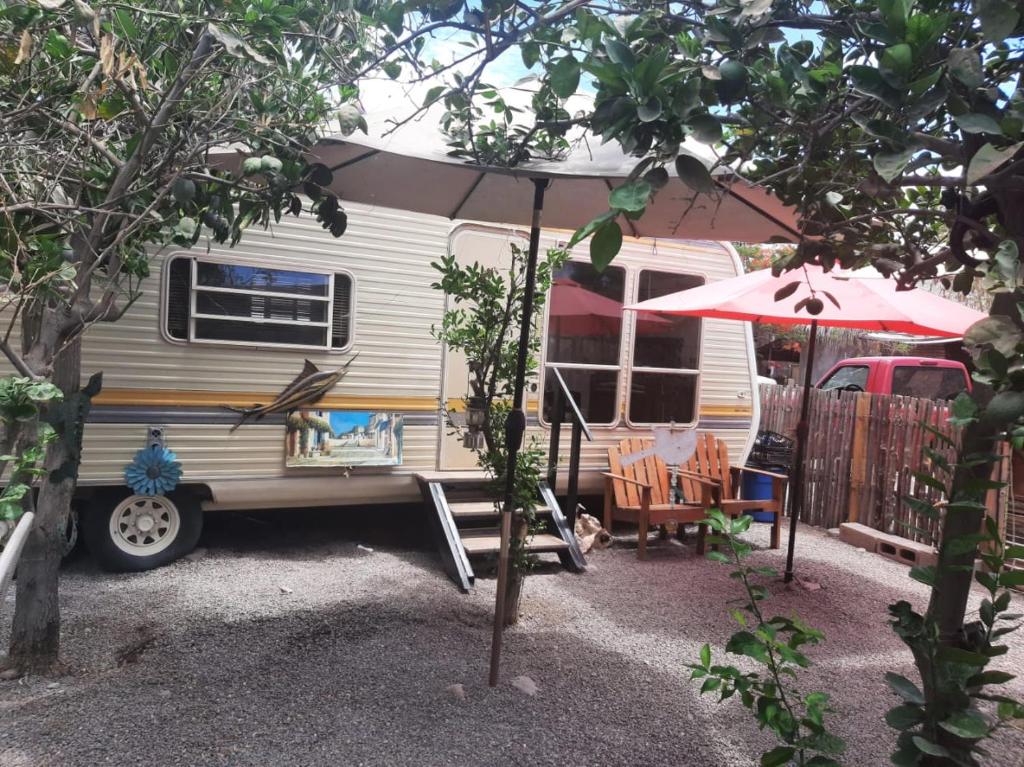 einen Wohnwagen mit einem Regenschirm, einem Tisch und Stühlen in der Unterkunft Casa rodante los cachorones in Loreto