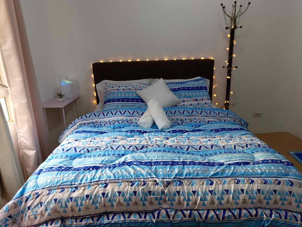 a bed with a blue comforter with lights on it at Rosecondotel in Manila