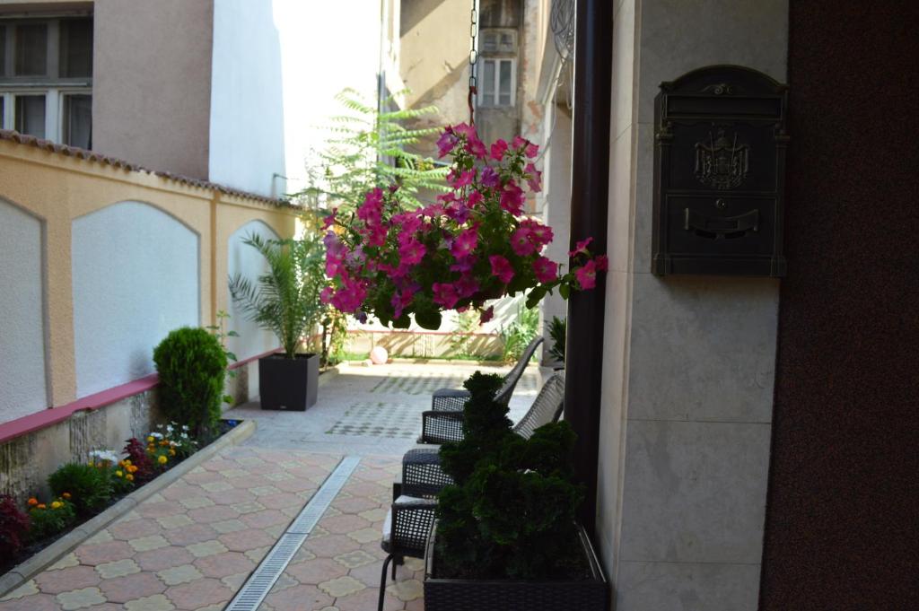 una fila de bancos con flores colgando de un edificio en Bon Bon Hotel, en Sofía