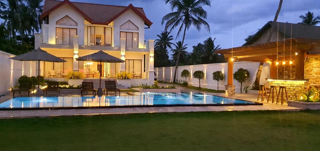 a house with a swimming pool in front of a house at Aryan Beach Villa in Wadduwa