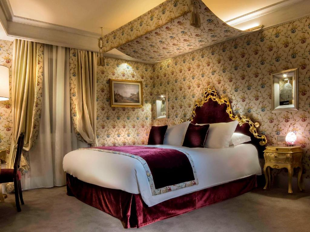 a bedroom with a large bed with floral wallpaper at Papadopoli Hotel Venezia - MGallery Collection in Venice
