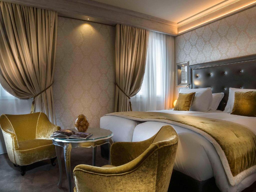 a hotel room with a bed and a table and chairs at Papadopoli Hotel Venezia - MGallery Collection in Venice