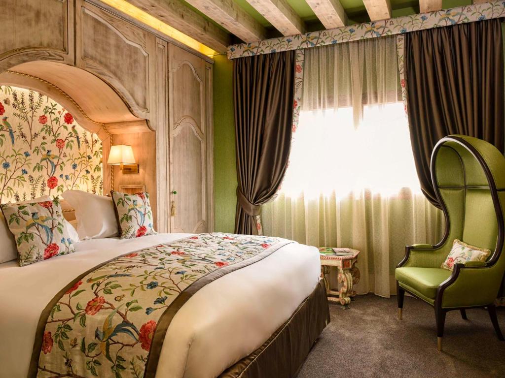 a bedroom with a bed and a chair and a window at Papadopoli Hotel Venezia - MGallery Collection in Venice