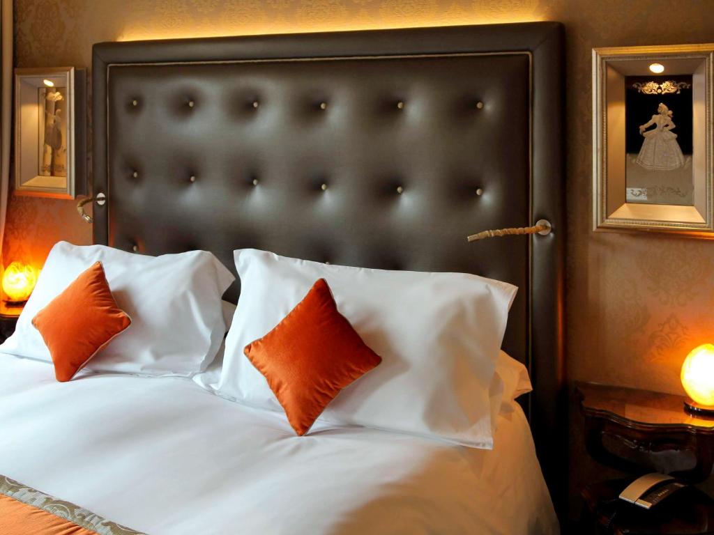 a bedroom with a bed with orange and white pillows at Hotel Papadopoli Venezia - MGallery Collection in Venice