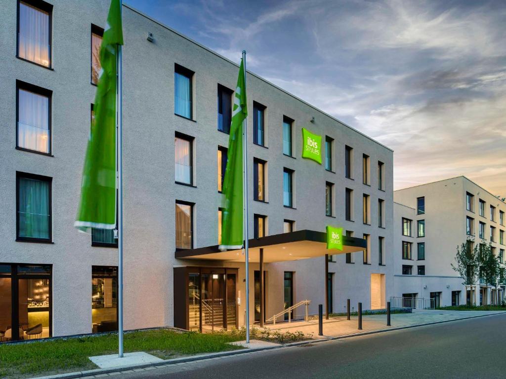 un bâtiment avec des drapeaux verts devant lui dans l'établissement ibis Styles Friedrichshafen, à Friedrichshafen