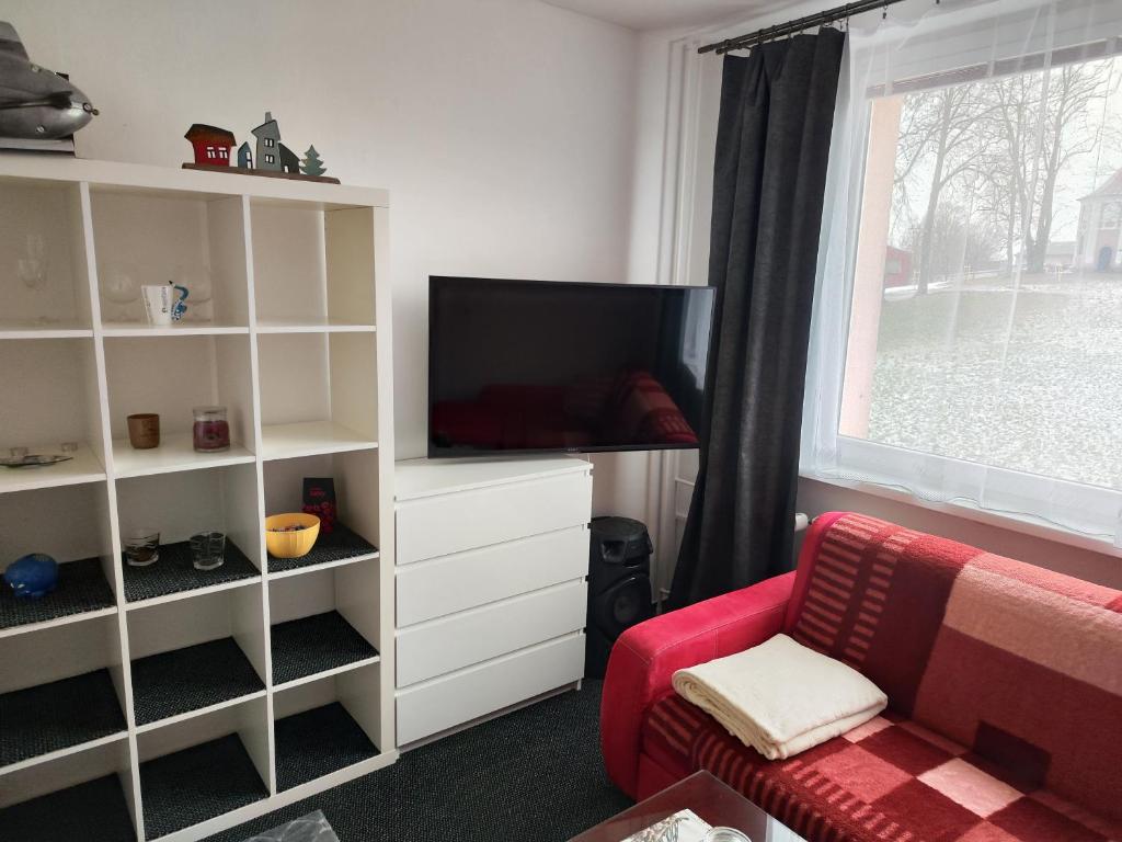 een woonkamer met een tv en een rode stoel bij Apartmán Rokytnička in Rokytnice v Orlických Horách
