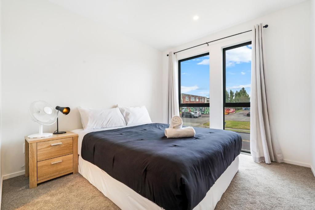 ein Schlafzimmer mit einem Bett und einem großen Fenster in der Unterkunft Cozy Brand New Townhouse 3 in Auckland
