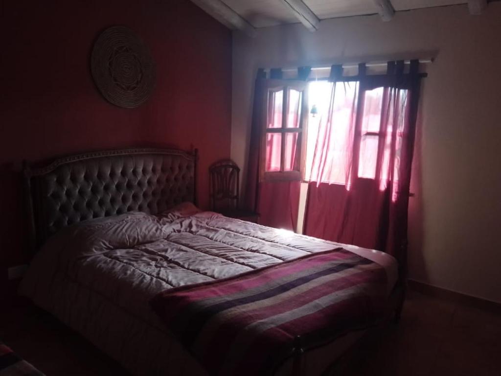 1 dormitorio con 1 cama y una ventana con cortinas rojas en Chakana en Villa Yacanto