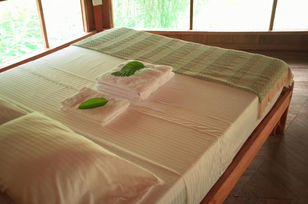 un letto con lenzuola bianche e asciugamani verdi di CHUNAKI ECOLODGES - Authentic Activities and Food in the Amazon a Zaragoza