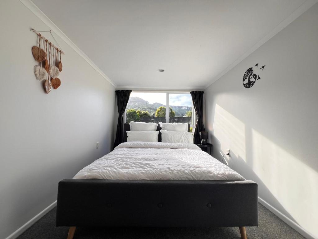 a bedroom with a bed with a window at Hill View Abode Tawa in Wellington