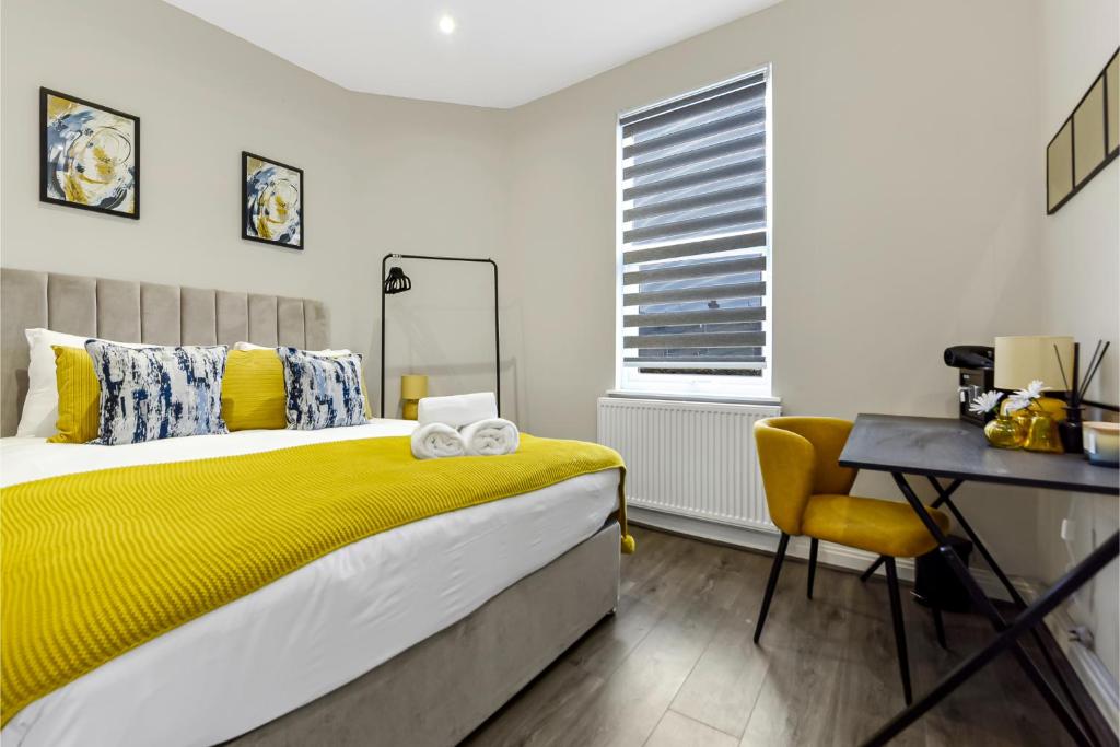 a bedroom with a yellow bed and a desk at City Getaway- Newly Renovated Flat for Groups in Greenford