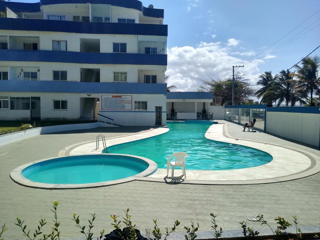 a swimming pool in front of a building at Apt 204 Frente Para o Mar e Piscina Village das Ondas in Piúma