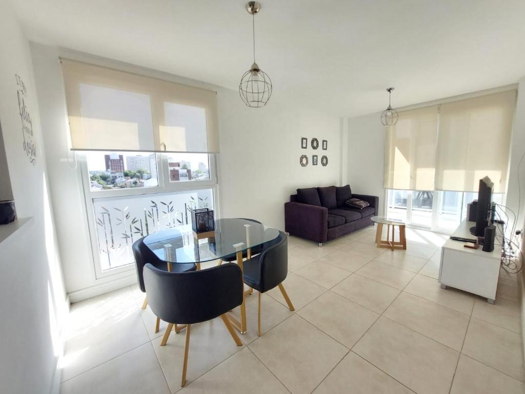 Messidor Mar del Plata Luminoso departamento 2 ambientes con cochera في مار ديل بلاتا: غرفة معيشة مع طاولة وكراسي زجاجية