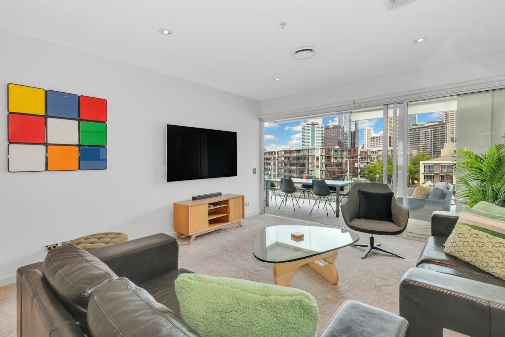 ein Wohnzimmer mit einem Sofa und einem TV in der Unterkunft QV Apartment Overlooking the Viaduct (1137) in Auckland