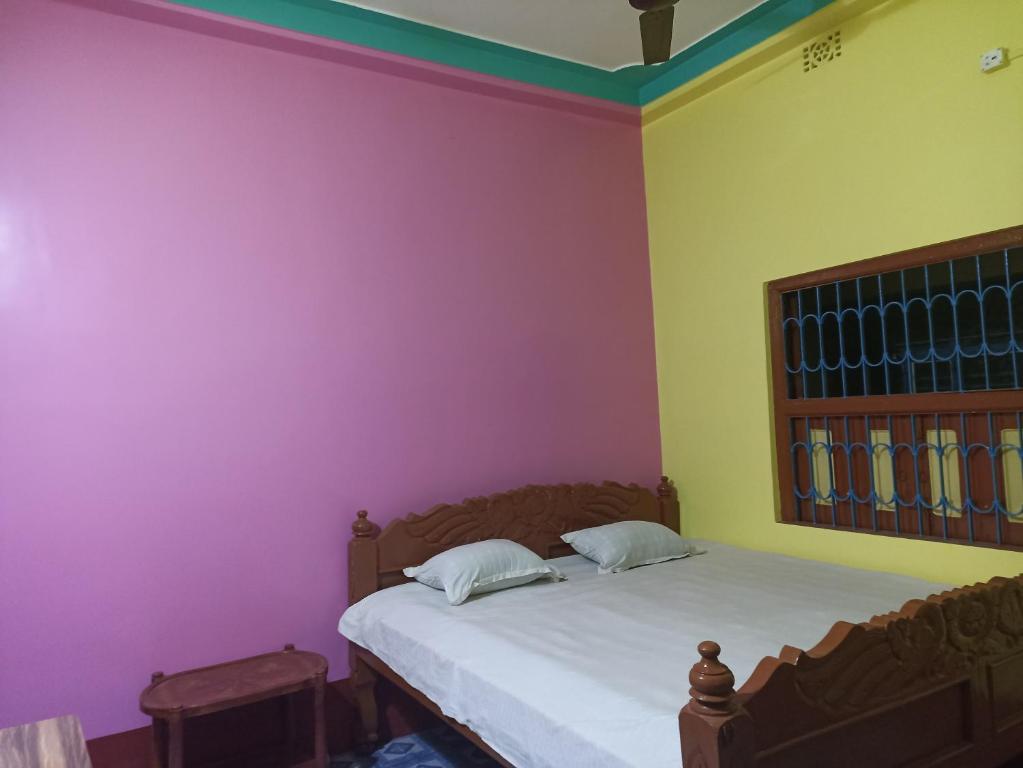 a bedroom with pink and yellow walls and a bed at Niraloy in Bolpur